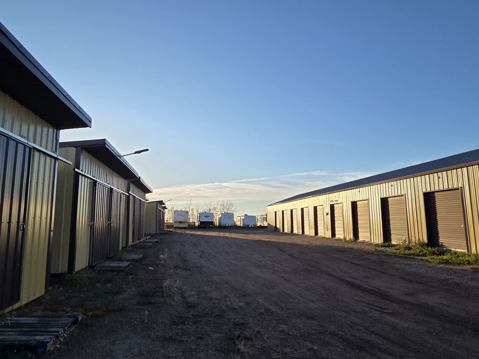 Rows of storage unit buildings along a gravel drive, with RVs parked at the far end
